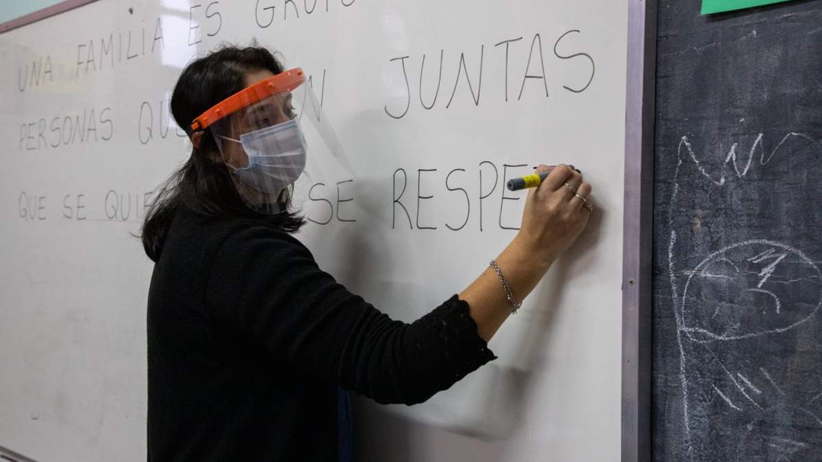Una docente escribe en la pizarra. Fuente: (Twitter)
