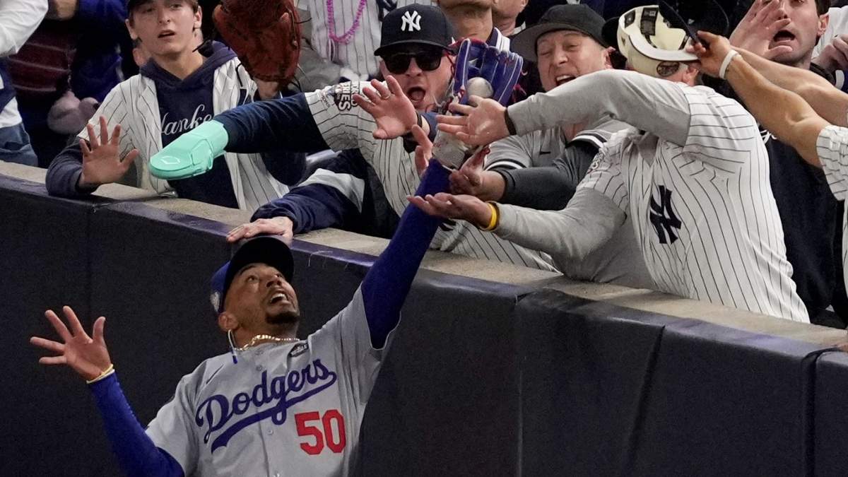 Fanáticos interfieren en foul elevado que atrapó por el jardinero derecho de los Dodgers, Mookie Betts.
