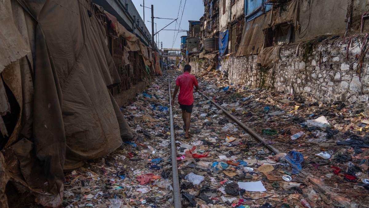 Un hombre camina en una vía ferroviaria repleta de plásticos y otros desechos en el Día de la Tierra, en Mumbai, India