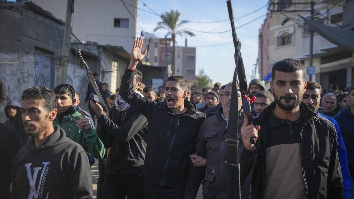 Familiares y vecinos, dos de ellos armados, caminan durante el cortejo fúnebre de una víctima de un ataque israelí contra una vivienda a última hora del sábado en el que murieron al menos ocho personas, en Deir al-Balah, en el centro de la Franja de Gaza