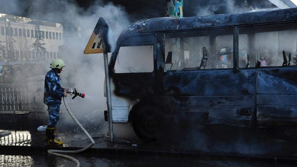 Un bombero extingue las llamas en un autobús tras una letal explosión, en Damasco, Siria