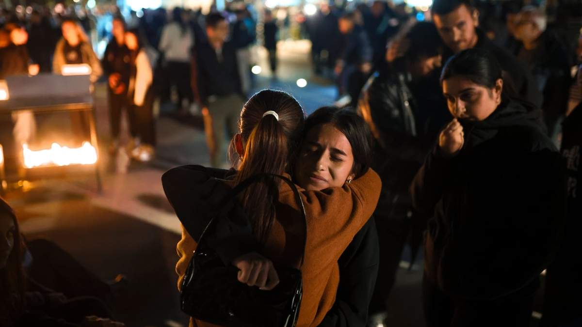 Gente abrazada mientras espera a encender velas en la ciudad de Kocani, Macedonia del norte, el domingo 16 de marzo de 2025, tras un gran incendio en un club nocturno la madrugada del domingo