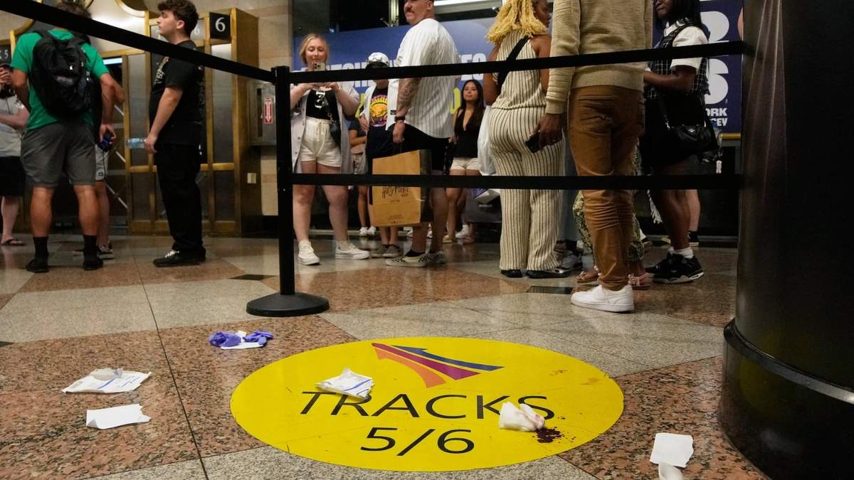 Gente de pie cerca de una zona acordonada tras un apuñalamiento en la estación Penn