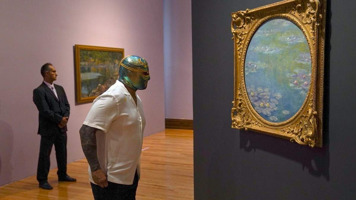 El luchador mexicano CintaDeOro observa una pintura de Claude Monet durante la inauguración de la exposición “Monet. Luces del Impresionismo” en la Ciudad de México