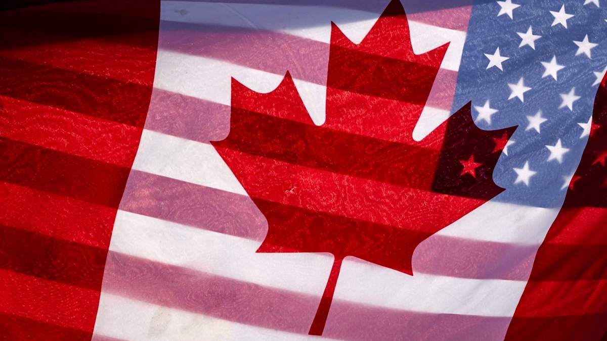 La luz del sol ilumina las banderas de Canadá y Estados Unidas, que un manifestante sostiene juntas en el exterior del Parlamento de Canadá, en Ottawa