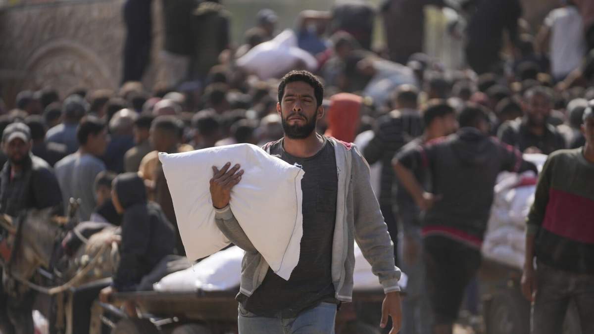 Palestinos se reúnen para recibir costales de harina distribuidos por la agencia de Naciones Unidas para los refugiados palestinos, UNRWA, el sábado 2 de noviembre de 2024, en Deir al Balah