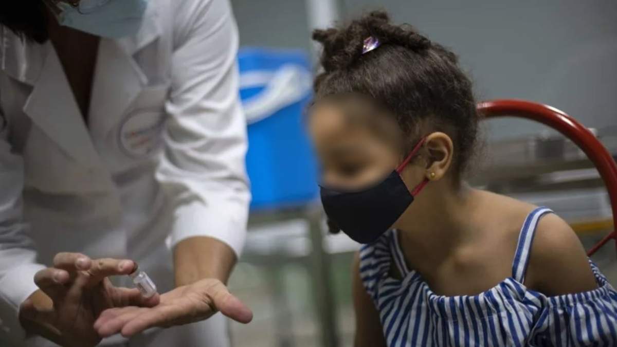 Una enfermera muestra la vacuna contra el covid-19 a una niña