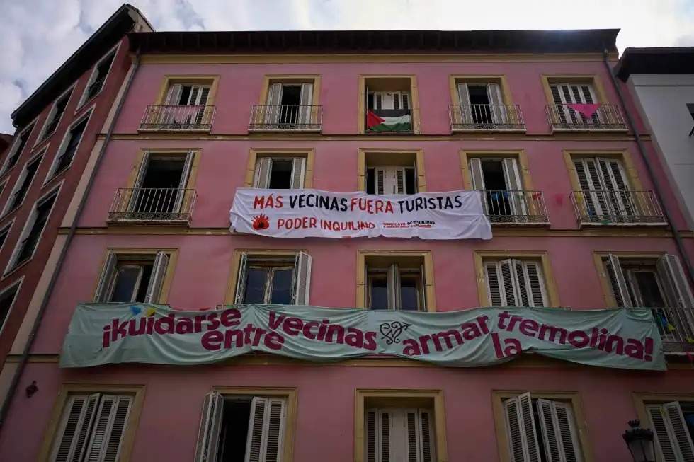 Pancartas contra los alquileres vacacionales turísticos cuelgan de la fachada de un edificio en el centro de Madrid, España, el martes 3 de junio de 2025. El texto en español dice: "Más vecinos, menos turistas. Poder de los inquilinos" y "Cuidándonos unos a otros como vecinos, animando el ambiente".