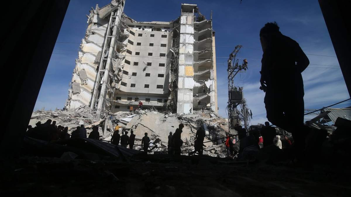 Palestinos caminan junto a un edificio residencial destruido en un ataque israelí en Rafah, Franja de Gaza