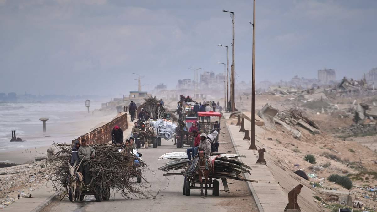 Palestinos desplazados, cargados con sus pertenencias, madera y otros artículos, van del sur al norte de Gaza por la carretera costera, lejos de las zonas donde opera el ejército israelí tras la reanudación de su ofensiva sobre la Franja, a las afueras de la Ciudad de Gaza