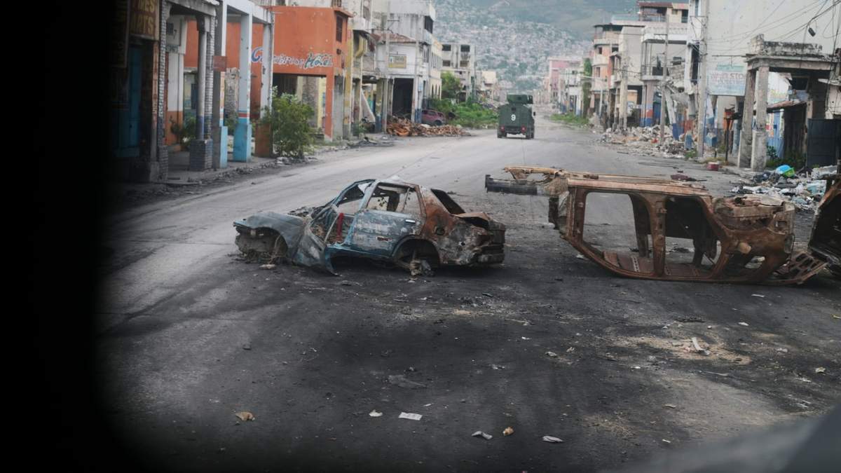 Carros chamuscados bloquean una calle, fotografiada desde un vehículo policial blindado que patrullaba una zona de Puerto Príncipe afectada por pandillas, el 16 de enero del 2026
