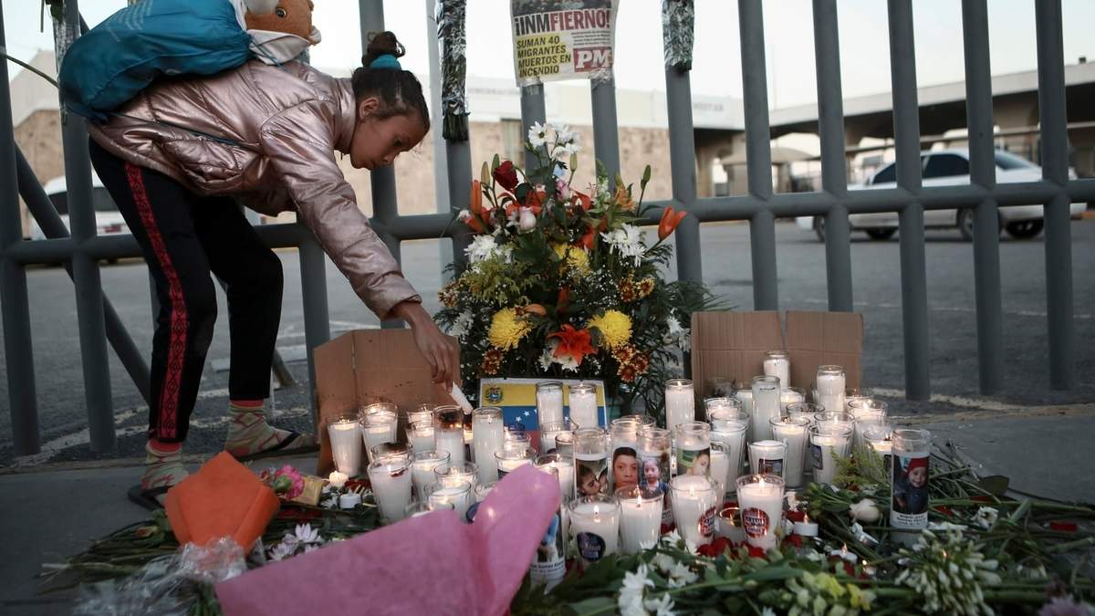 Una menor enciende una vela frente al centro de detención de migrantes en Ciudad Juárez