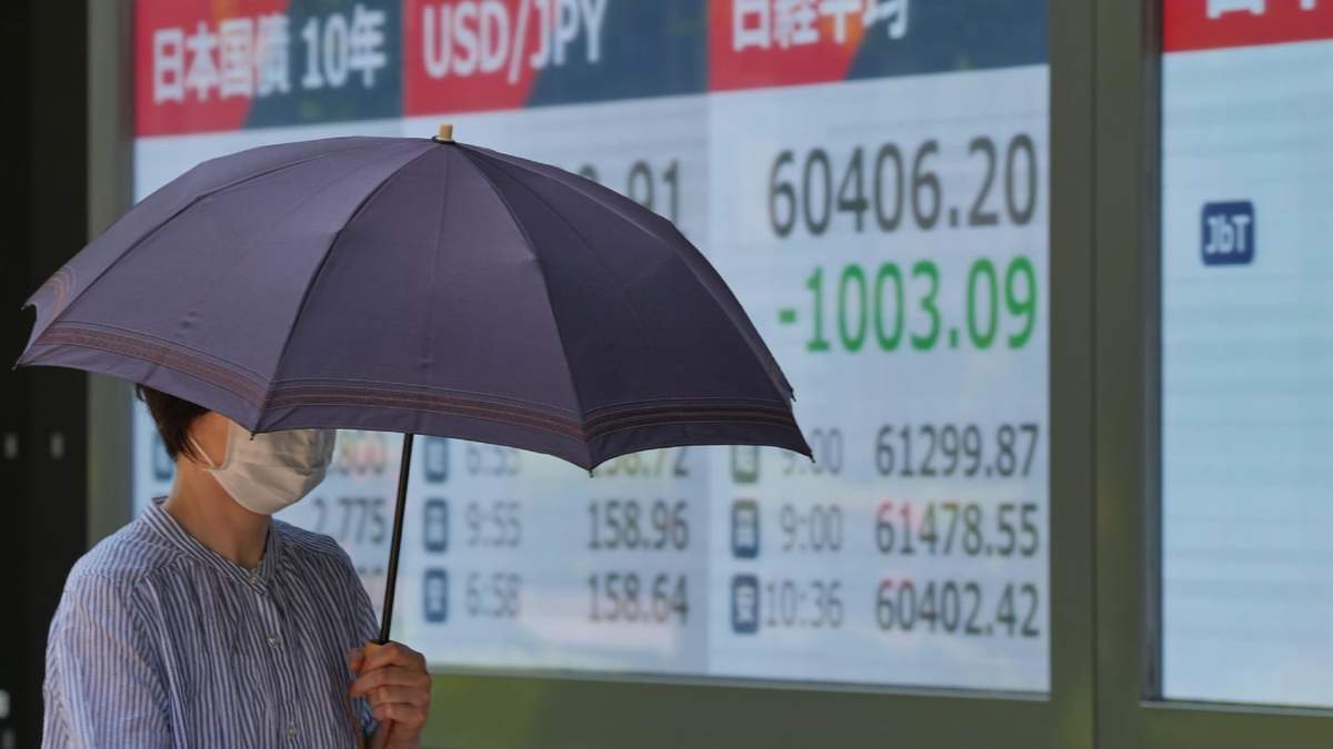 Una persona camina frente a una pantalla electrónica que muestra el índice Nikkei de Japón en una firma de valores, el lunes 18 de mayo de 2026, en Tokio