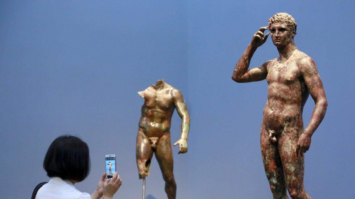 ARCHIVO - La reportera Sookee Chung toma una foto a una escultura llamada "Juventud victoriosa", hecha entre el 300 aC y el 100 aC, en el Museo J. Paul Getty en Los Ángeles