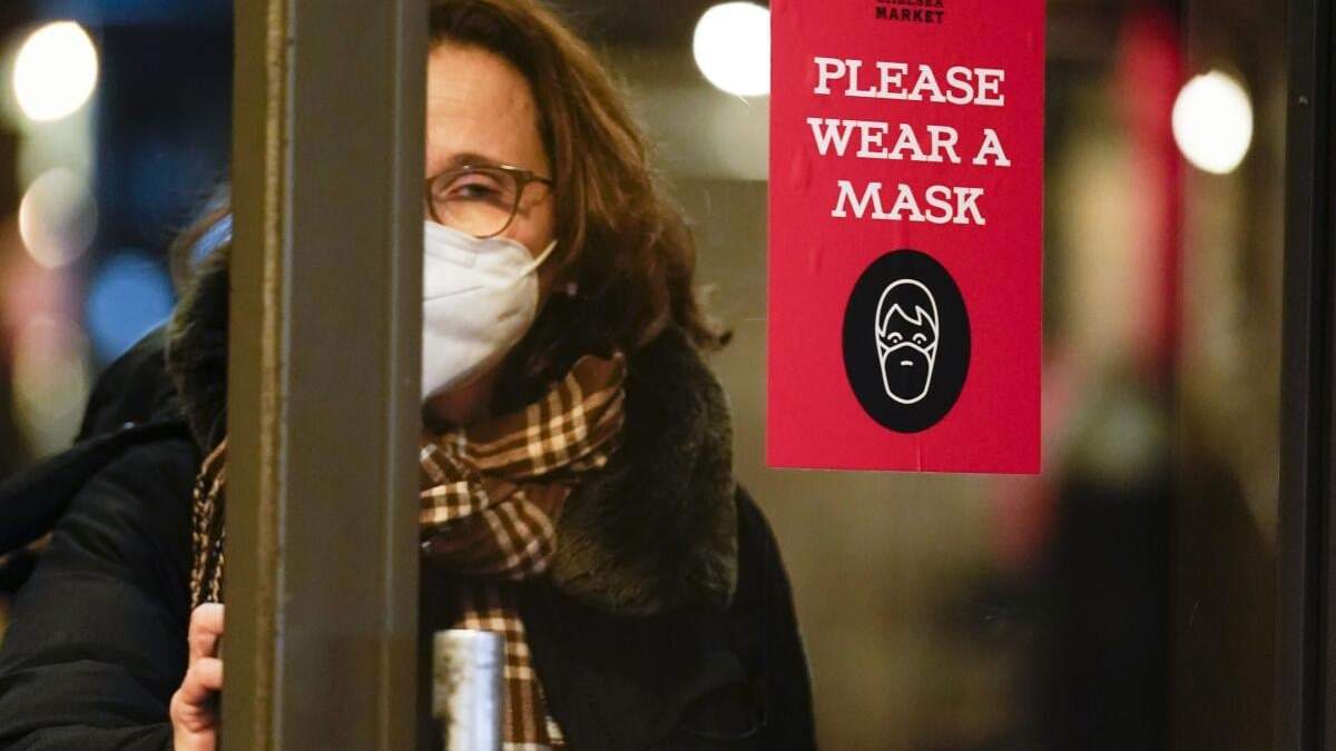 Una mujer pasa una puerta en la que se pide a los clientes que usen mascarilla, Nueva York, 9 de febrero de 2022