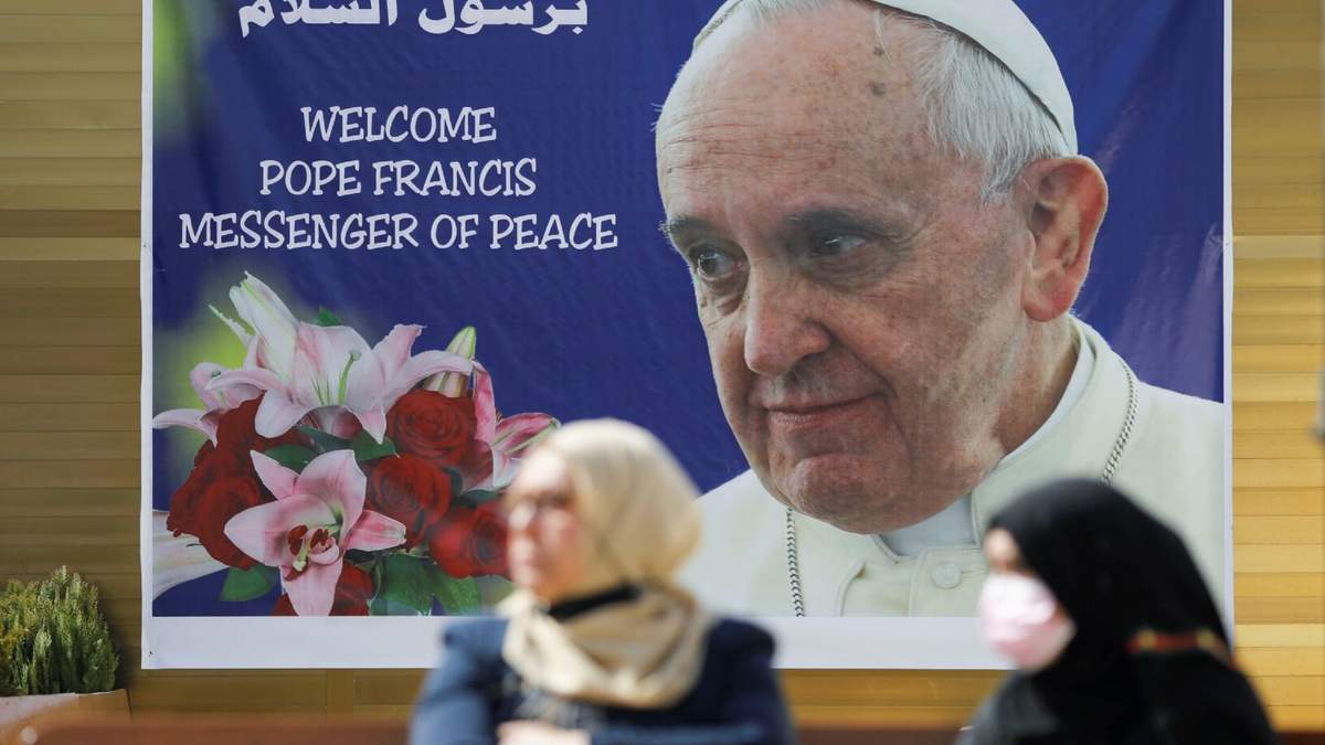 Dos mujeres frente a una pancarta de bienvenida para el papa Francisco en Irak. Fuente: (Twitter)