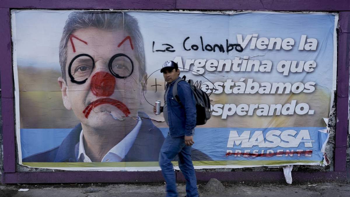 Un hombre camina al lado de una pancarta pintarrajeada del ministro de Economía Sergio Massa
