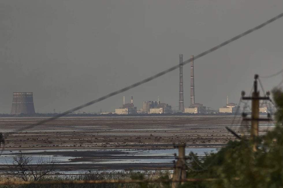 La central nuclear de Zaporiyia, vista al fondo tras la crecida provocada por la rotura de la represa de Kajovka, en Energodar, en Ucrania, el 27 de junio de 2023
