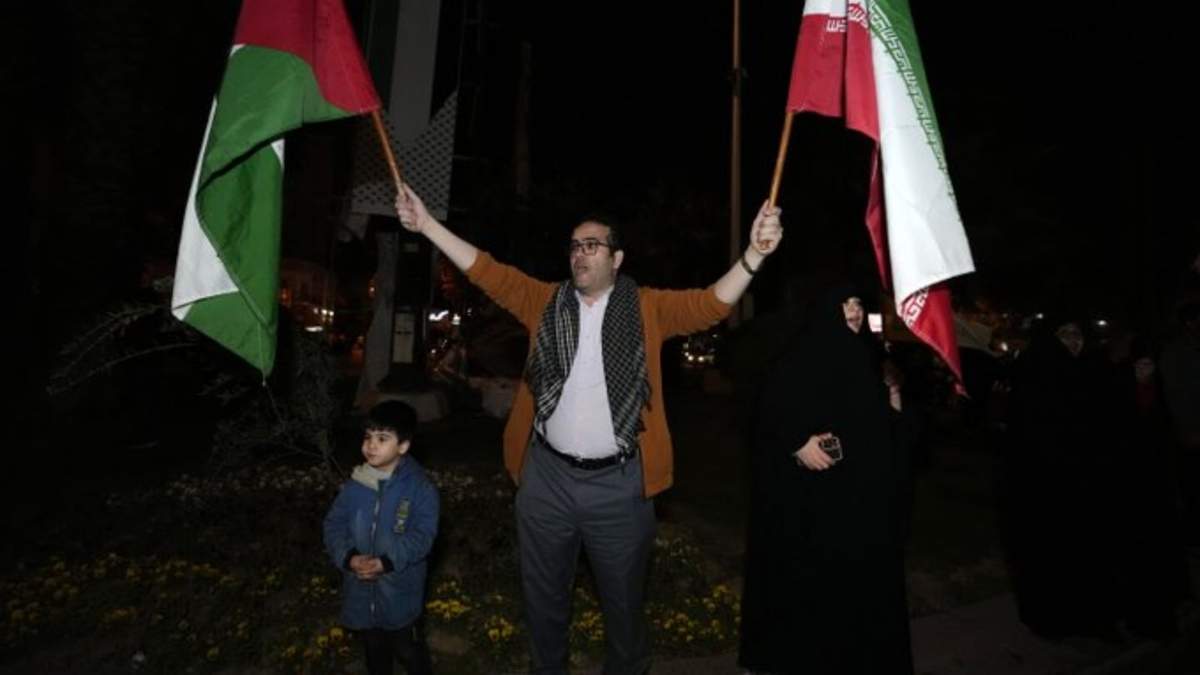 Un manifestante ondea banderas iraníes y palestinas durante una protesta anti-Israel en la Plaza Palestina en Teherán, Irán, la madrugada del domingo 14 de abril de 2024