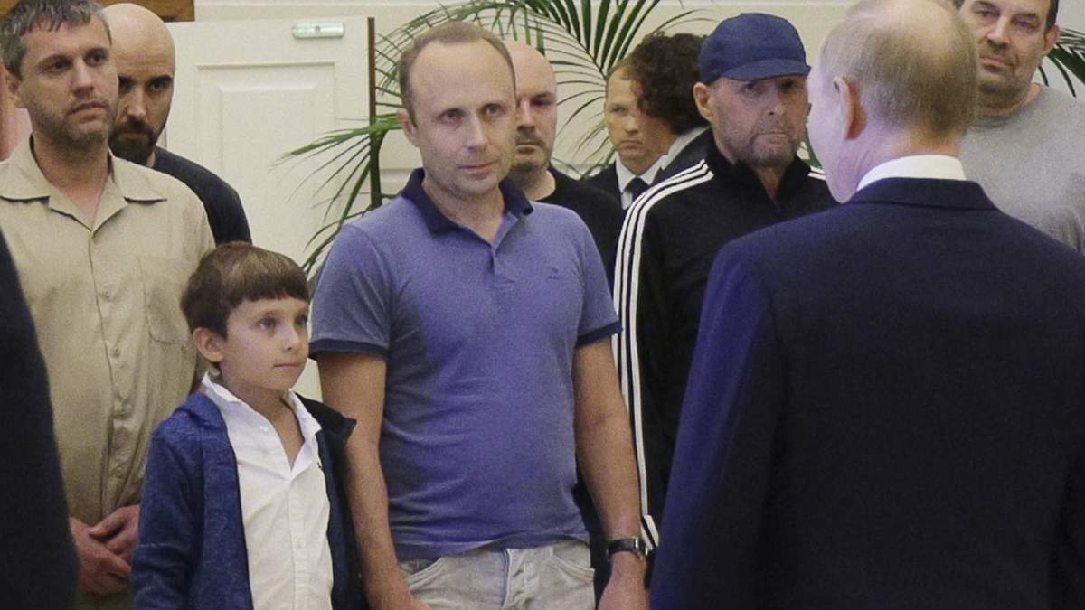 Un hombre identificado como Pablo González, un periodista independiente español que trabajaba en Polonia desde 2019, segundo por la izquierda con la cabeza afeitada, escucha al presidente de Rusia, Vladímir Putin, que aparece de espaldas, mientras habla a prisioneros rusos liberados, dentro del canje de prisioneros más numeroso entre Estados Unidos y Rusia en la era postsoviética, a su llegada al aeropuerto de Vnukovo, a las afueras de Moscú, Rusia, el jueves 1 de agosto de 2024. González tenía otro pasaporte y otro nombre: Pavel Rubtsov