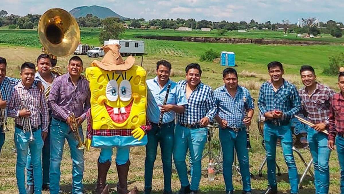El grupo musical con todo y botarga posa delante del socavón