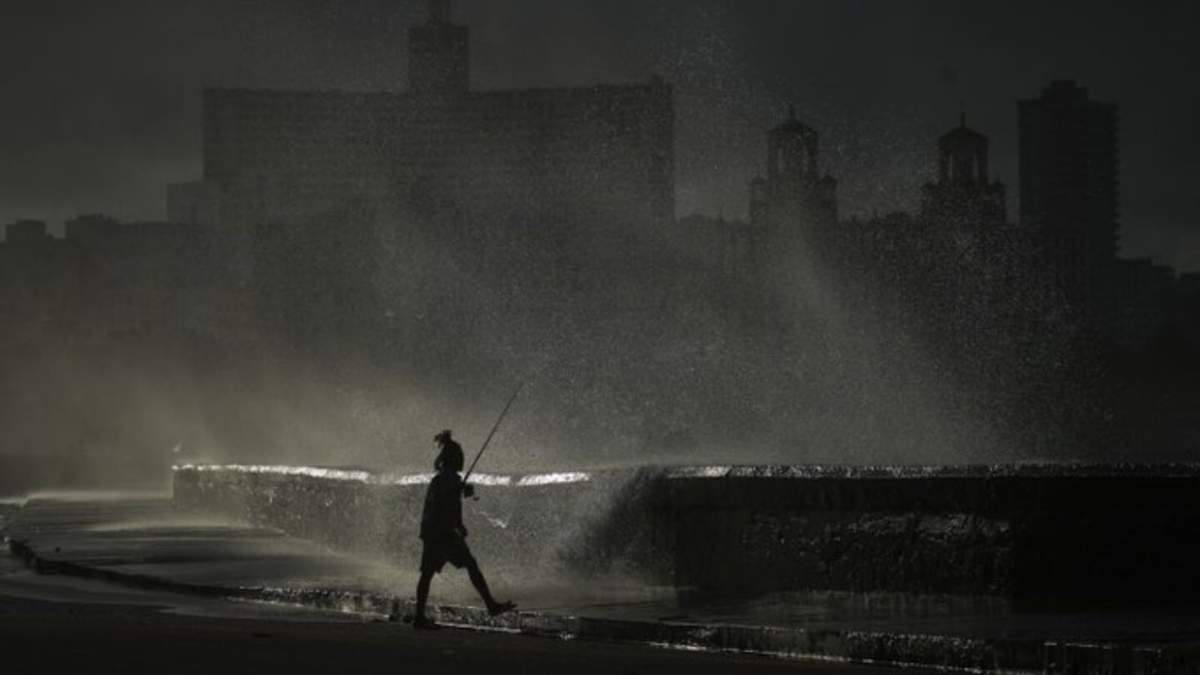 Una persona pesca a lo largo del malecón mientras las olas rompen durante un corte de energía en La Habana, Cuba