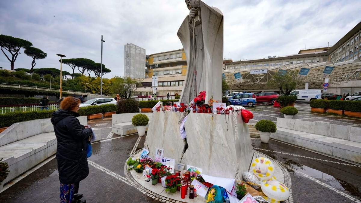 Una mujer reza por el papa Francisco frente a la estuta de San Juan Pablo II, a la entrada del hospital Agostino Gemelli de Roma, donde el pontífice argentino está ingresado desde el 14 de febrero
