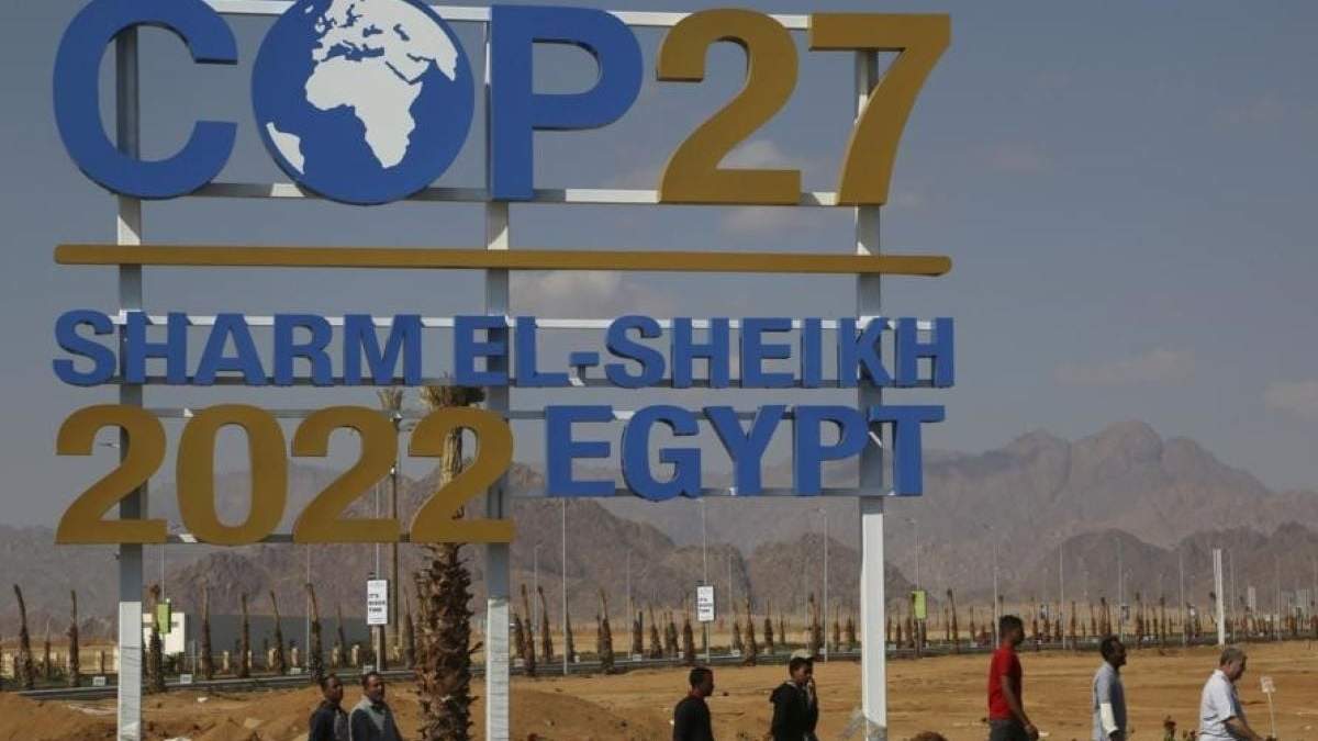 Trabajadores pasan por un letrero de la Cumbre de la ONU COP27, llevada a cabo en Sharm el-Sheikh, Egipto