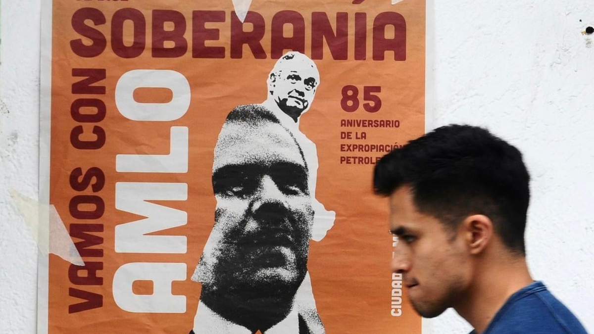 Un hombre pasa frente a un cartel que invita a la concentración del 18 de marzo