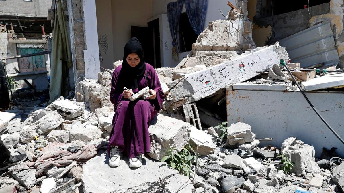 La artista Saja Moussa sobre los restos de la casa de su familia en el campo de refugiados de Rafah, en Gaza