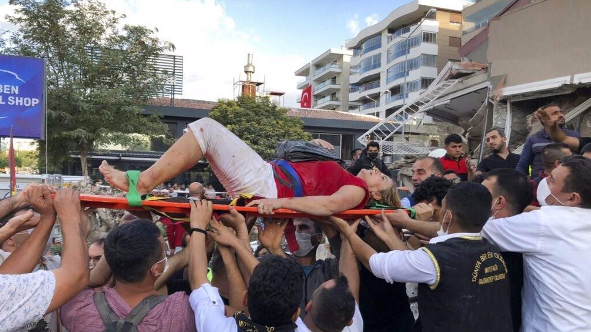 Voluntarios y rescatistas trasladan a una mujer hallada entre los escombros de un edificio derrumbado en Turquía