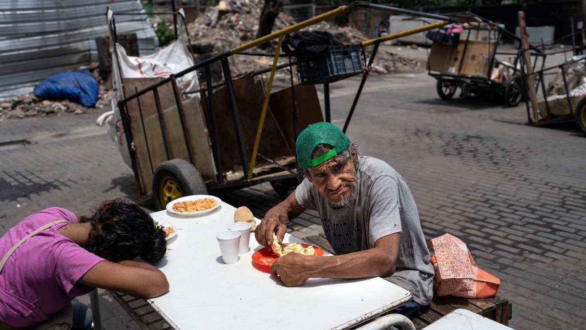 Dos personas almorzando una comida gratuita del comedor social de la Casa Comunitaria del Fondo, en el barrio Padre Carlos Múgica de Buenos Aires, Argentina